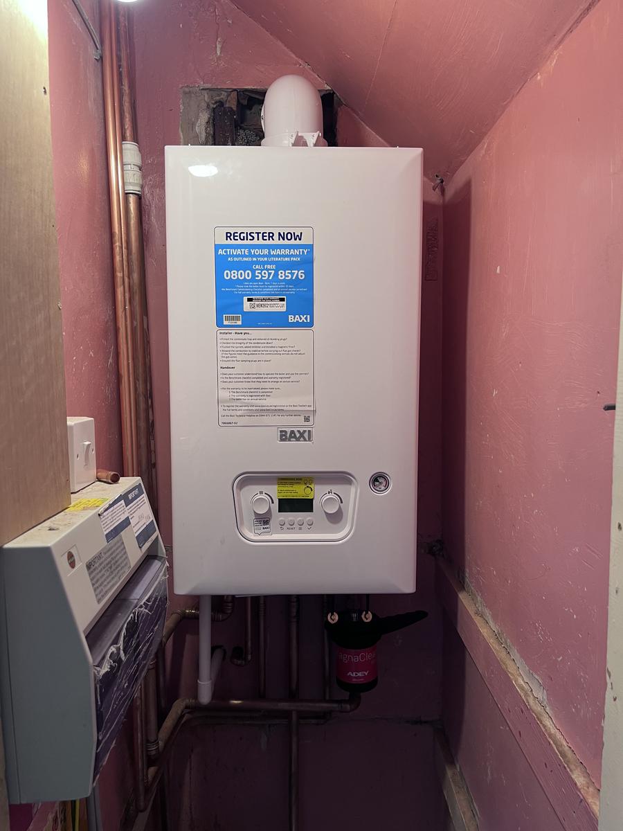 Boiler relocated downstairs and neatly installed inside a cupboard with re-run pipework